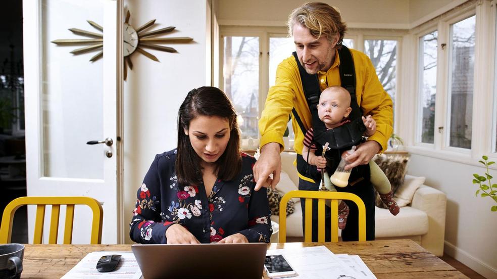 A couple with baby looking at laptop